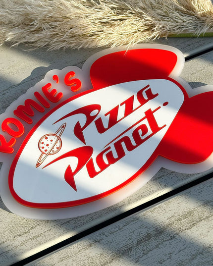Personalised Pizza Planet wall sign on a wooden surface with pampas grass.