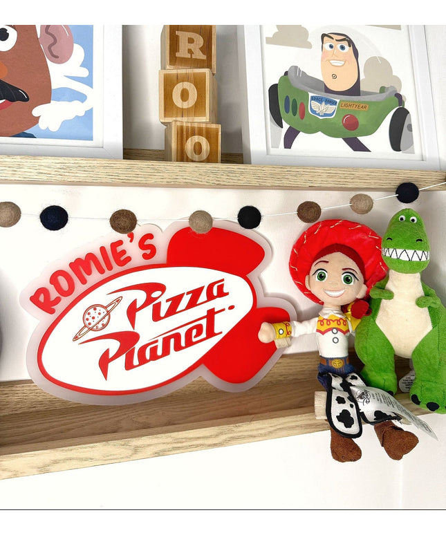 Shelf with 'Rommie's Pizza Planet' sign, toy figures, and framed pictures of cartoon characters.